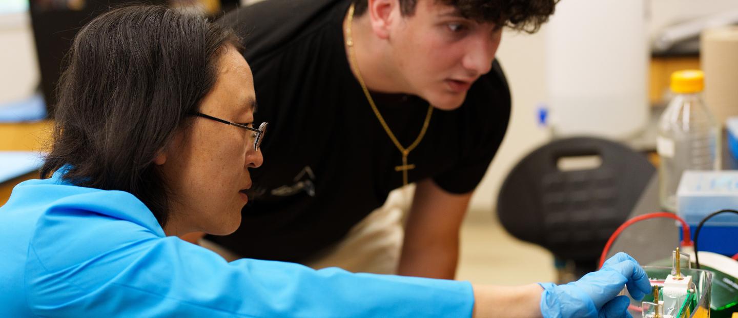 Two people working on a piece of equipment in a classroom